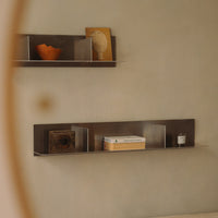 Minimalist shelving in earthy tones, featuring a geometric gray pattern, with warm orange and neutral decor accents.