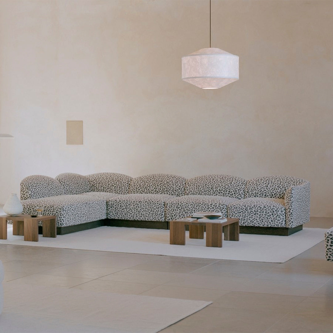 Luxe sectional sofa in soft white with abstract black patterns, complemented by natural wooden accents.