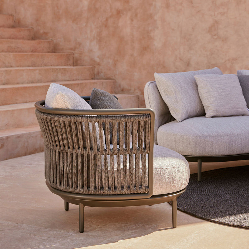 Light gray upholstered curved sofa with vertical wooden slats and a neutral color palette, featuring soft accent pillows.