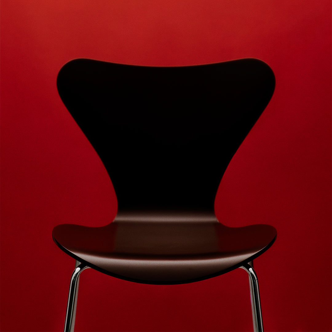 Black chair with a unique butterfly shape against a vibrant red background, showcasing sleek design and modern style.