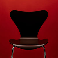 Black chair with a unique butterfly shape against a vibrant red background, showcasing sleek design and modern style.