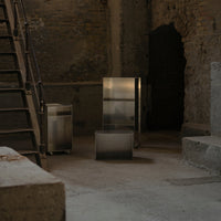 Modern metallic appliances in a rustic, dimly lit industrial setting with concrete and stone surfaces.