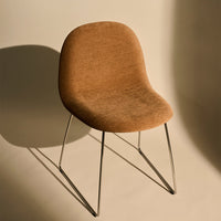 Brown upholstered chair with a smooth texture and sleek metal legs, set against a soft beige background.