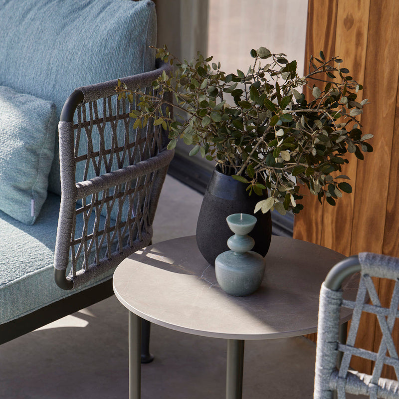 "Modern outdoor seating in light blue with woven details, paired with gray and matte black accents on a round table."