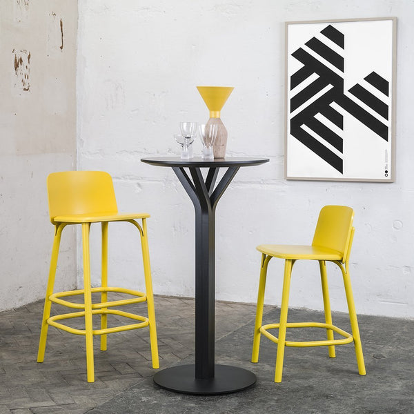 "Modern bar set featuring bright yellow stools and a sleek black table against a minimalist background."
