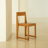Wooden chair in warm honey tones with a smooth, minimalist design against a neutral background.