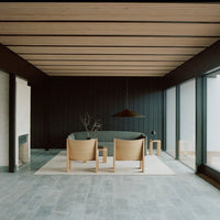 Modern living room with dark wood paneling, beige furniture, and gray floor tiles, creating a tranquil color palette.