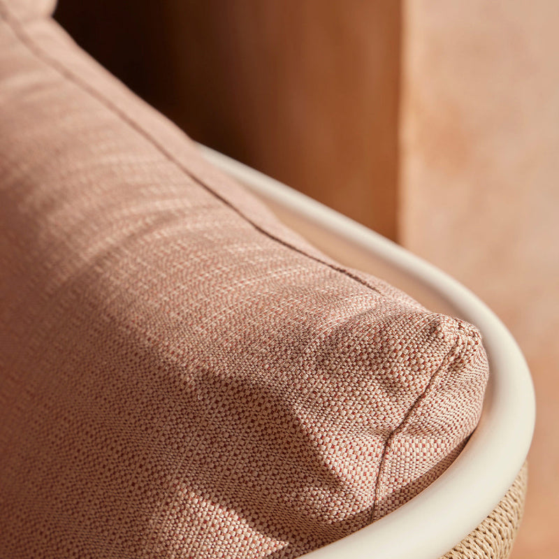 "Close-up of soft pink textured fabric cushion with a smooth cream trim."