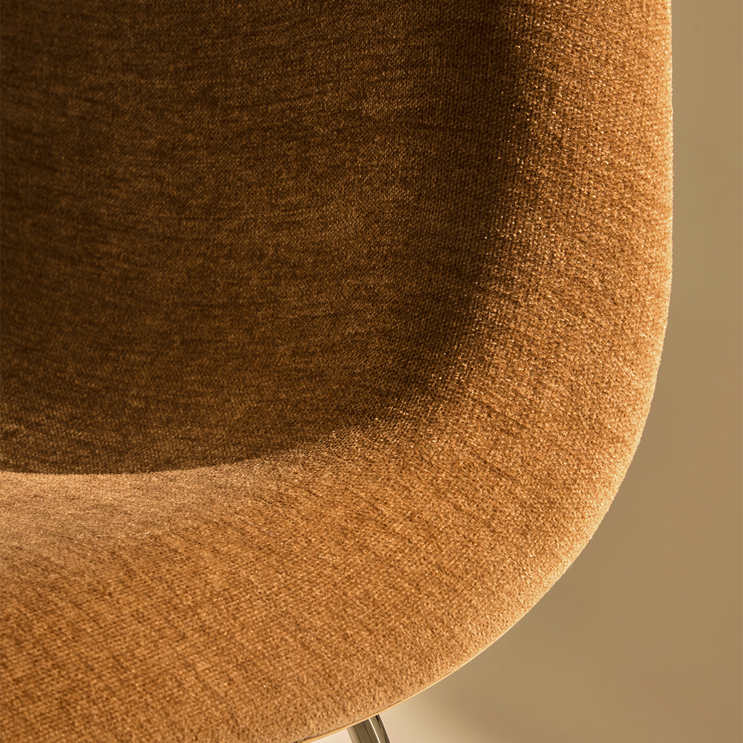 Close-up of textured, warm brown fabric featuring a subtle, soft pattern on a stylish chair.