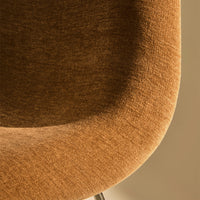 Close-up of textured, warm brown fabric featuring a subtle, soft pattern on a stylish chair.