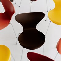 "Modern chair in deep brown surrounded by vibrant red and yellow chairs on a minimalist white background."