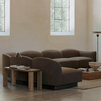Modern brown sectional sofa with smooth curves and a chic design, complemented by a beige and wooden coffee table.