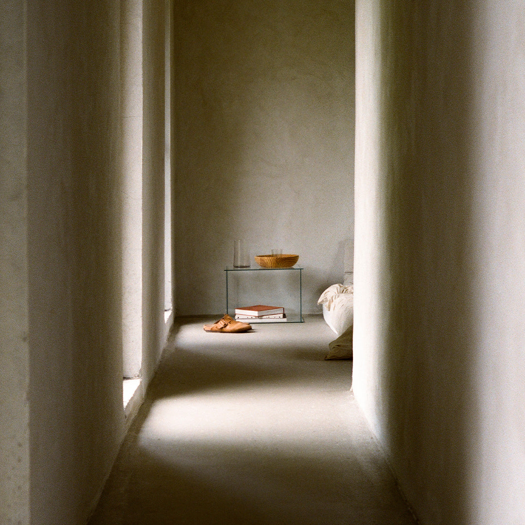 Neutral gray walls with soft cream tones and warm wooden accents create a serene, minimalist hallway aesthetic.