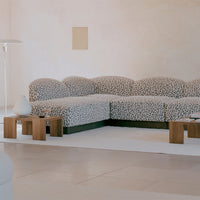 Black and white spotted fabric sectional sofa with green base in a minimalist room setting.
