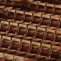 Repetitive pattern of wooden chair silhouettes in warm brown tones, creating a rich textured effect.