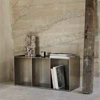 Sleek metallic storage unit with a minimalist design, featuring neutral tones and subtle textures against a rustic backdrop.