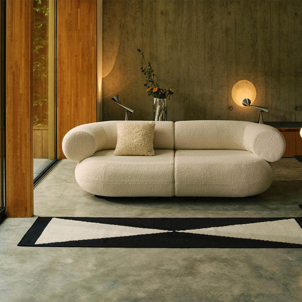 Cream-colored sofa with textured fabric, paired with a black and cream geometric rug in a modern living space.