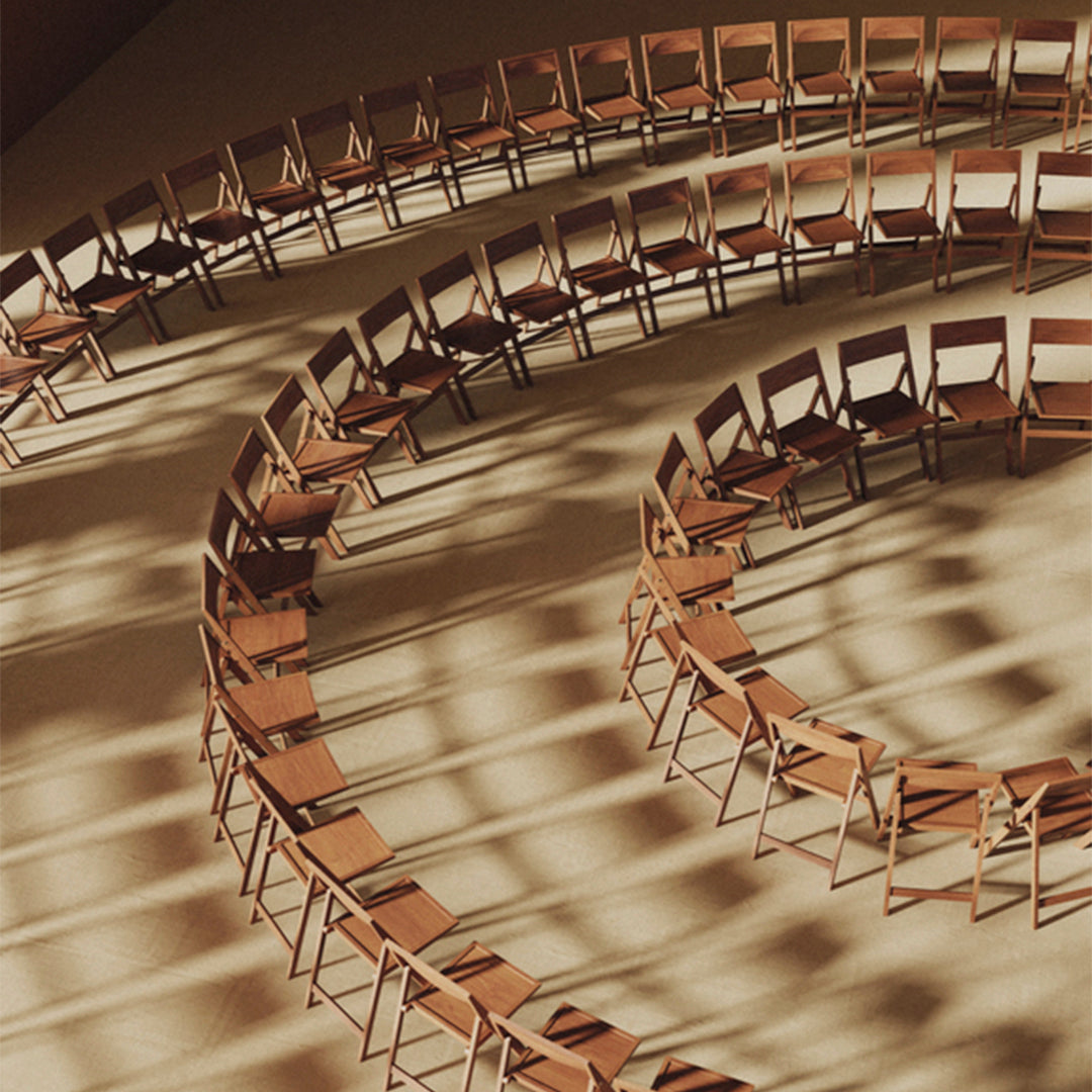 Wooden folding chairs arranged in a spiral formation, casting dynamic shadows against a warm, neutral backdrop.