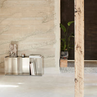 Modern silver console table against a textured beige wall with earthy tones and natural wood accents.