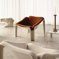 Modern chair featuring a warm orange upholstery with a minimalist design and neutral tones in a bright interior setting.