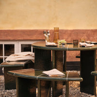 "Dark green glossy table set with light beige fabrics and subtle geometric patterns, perfect for outdoor gatherings."