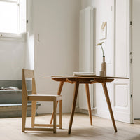 Light wooden dining table and chair with a minimalist design, featuring natural tones and clean lines in a bright space.