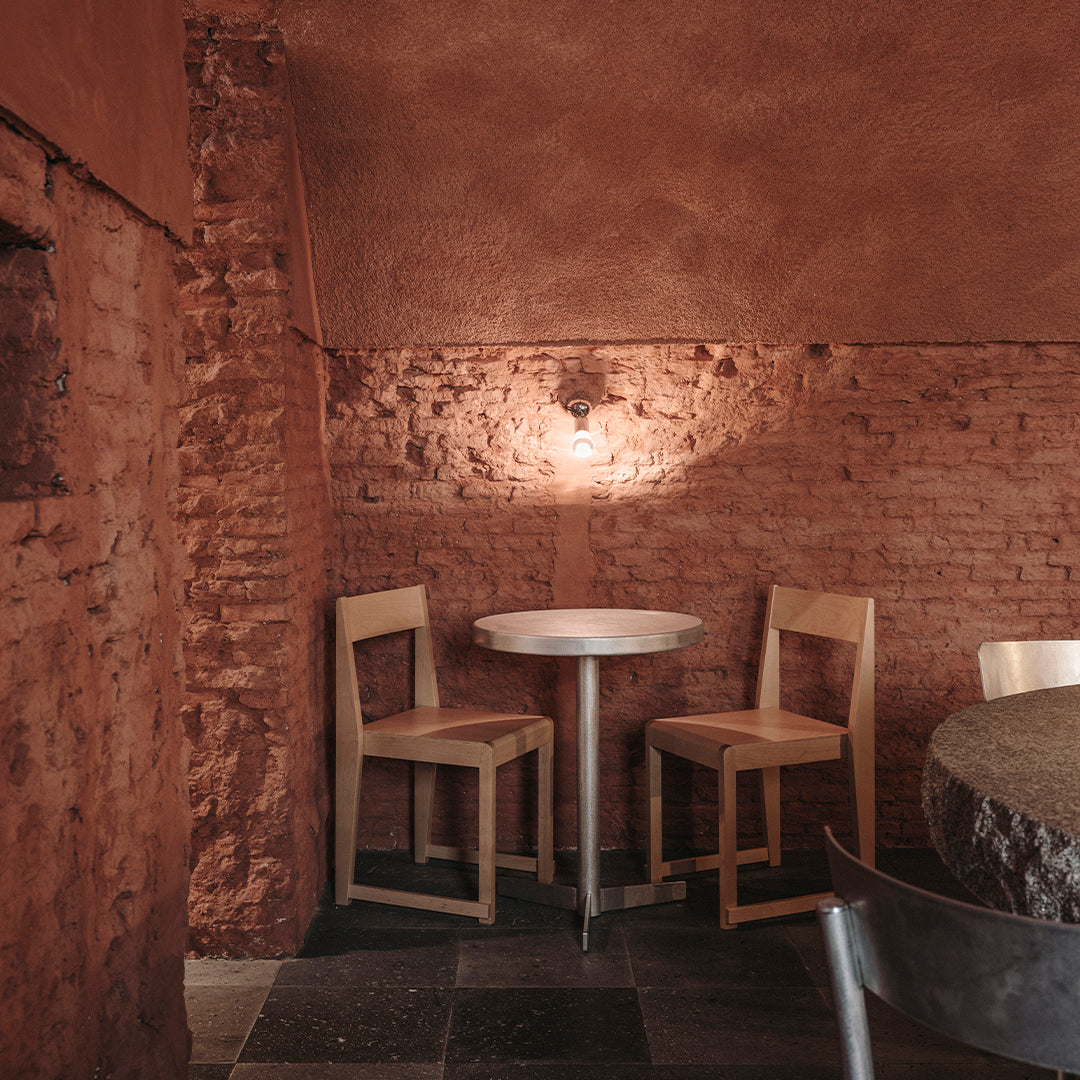 "Rustic red walls, natural wood chairs, and a simple round table create a warm, inviting atmosphere."