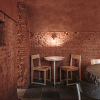 "Rustic red walls, natural wood chairs, and a simple round table create a warm, inviting atmosphere."