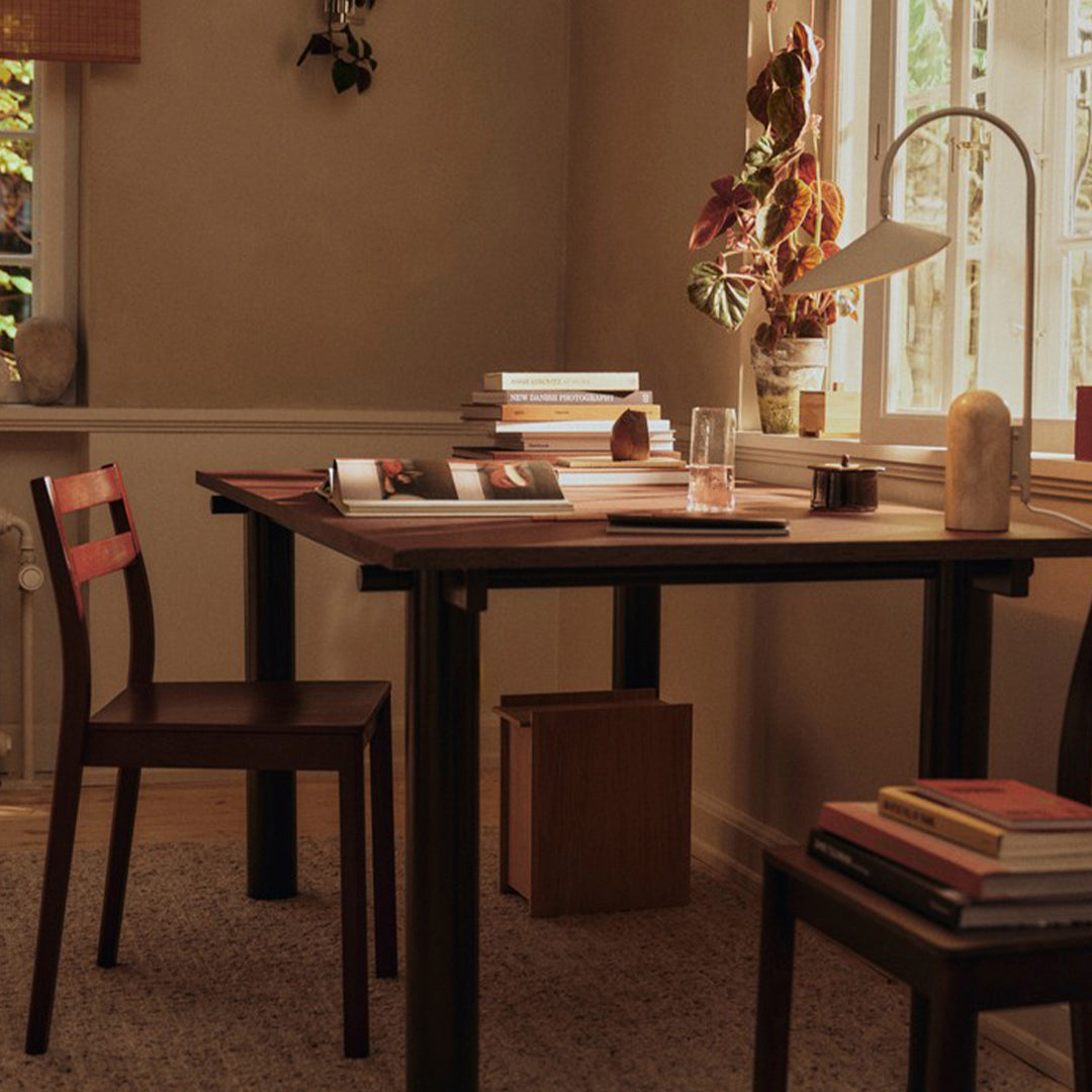Dark wood table and chair with a neutral beige wall, enhanced by earthy tones and soft textures in natural light.