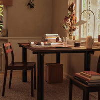 Dark wood table and chair with a neutral beige wall, enhanced by earthy tones and soft textures in natural light.