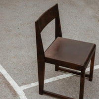 Dark brown wooden chair with a simple, modern design and a smooth, unembellished surface.