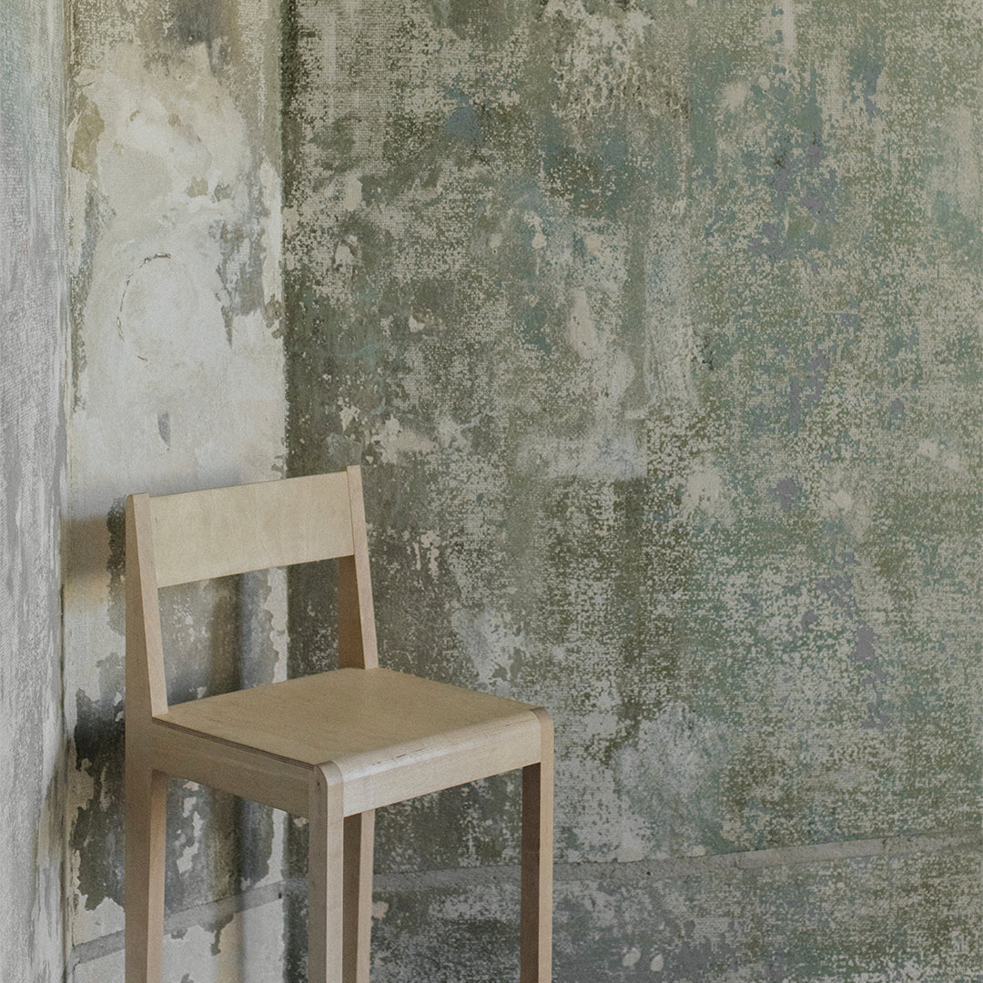 Light wood chair against a textured gray and green wall with subtle patterns. Perfect for minimalist decor.