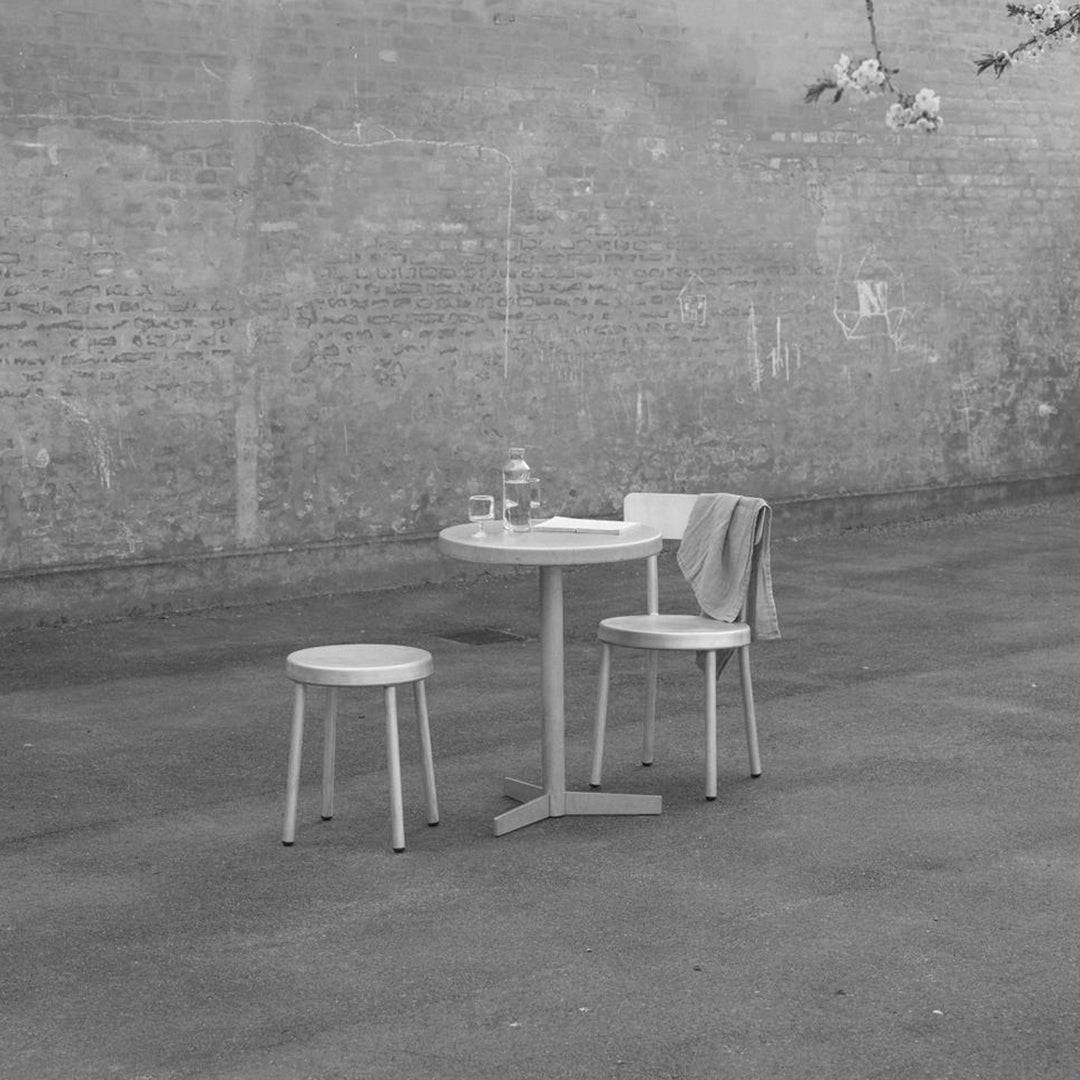 Minimalist black and white outdoor table set featuring a round table and two simple chairs on a concrete surface.