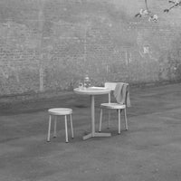 Minimalist black and white outdoor table set featuring a round table and two simple chairs on a concrete surface.