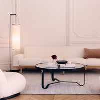 Modern living room featuring a white sofa, beige pillow, and black round coffee table on a light textured rug.