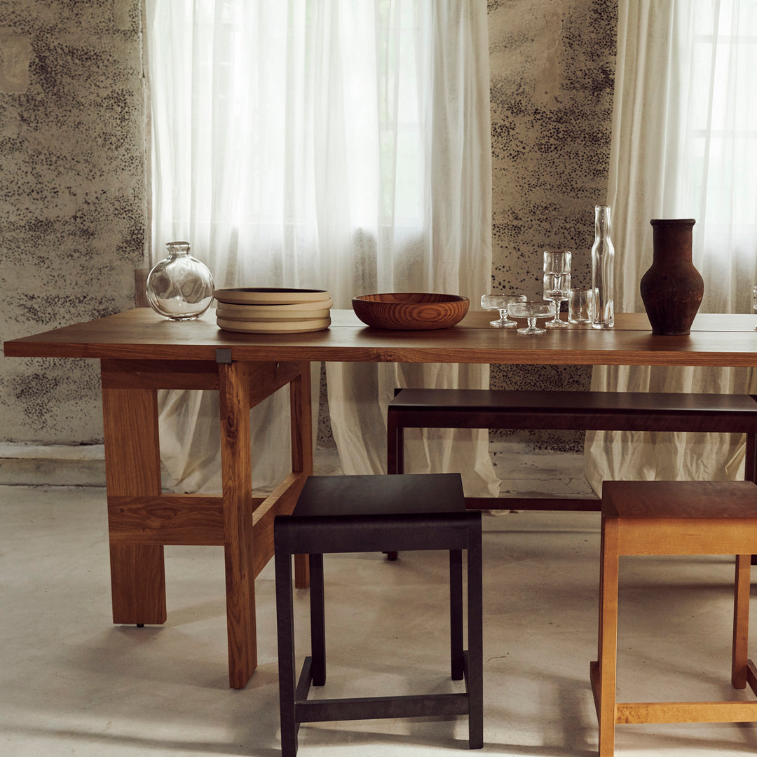 Elegant wooden table with neutral tones, featuring smooth, natural textures, complemented by earthy bowls and glassware.