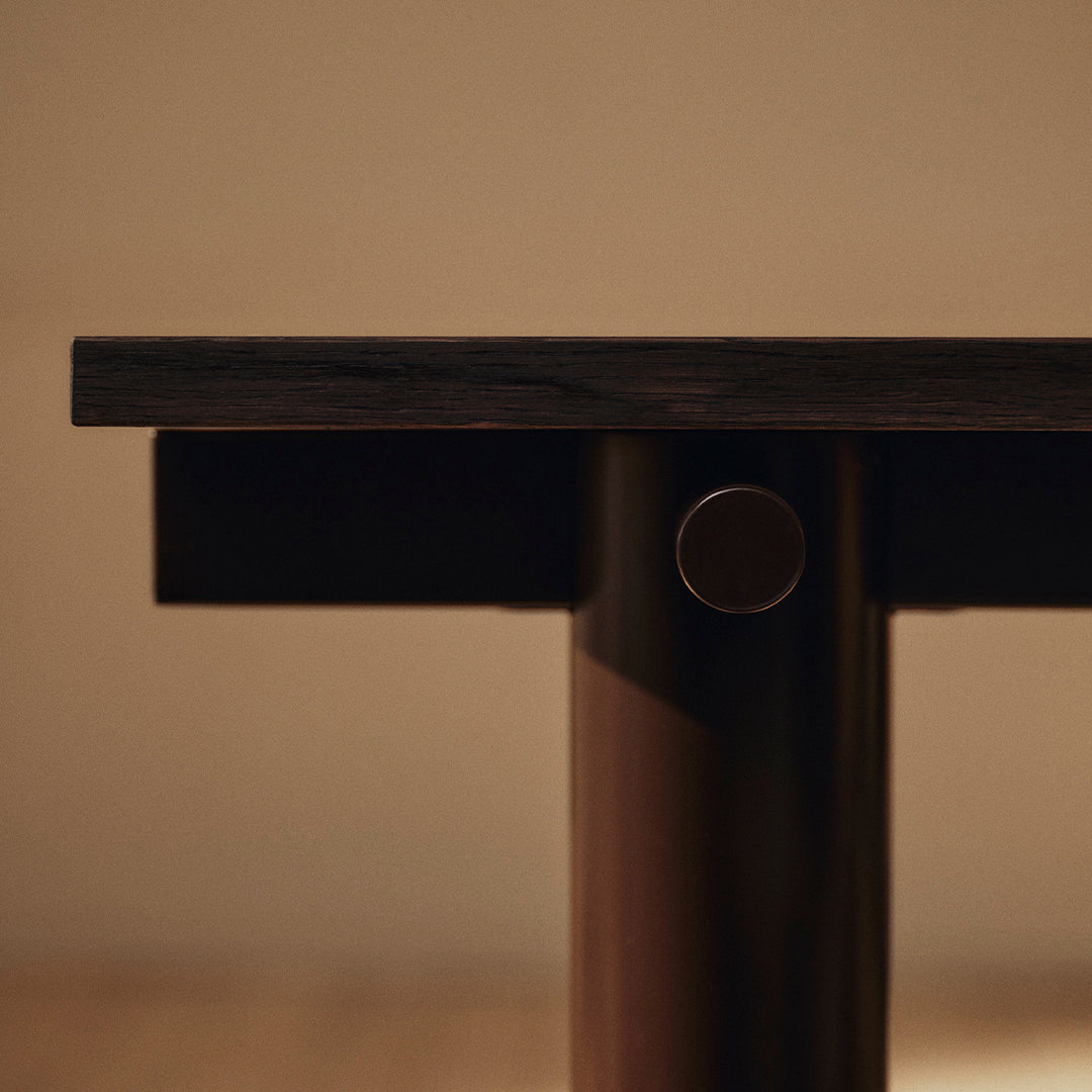 Dark wood tabletop with smooth, matte finish and contrasting polished metal accent, minimalistic design.