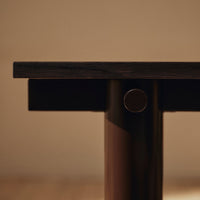 Dark wood tabletop with smooth, matte finish and contrasting polished metal accent, minimalistic design.