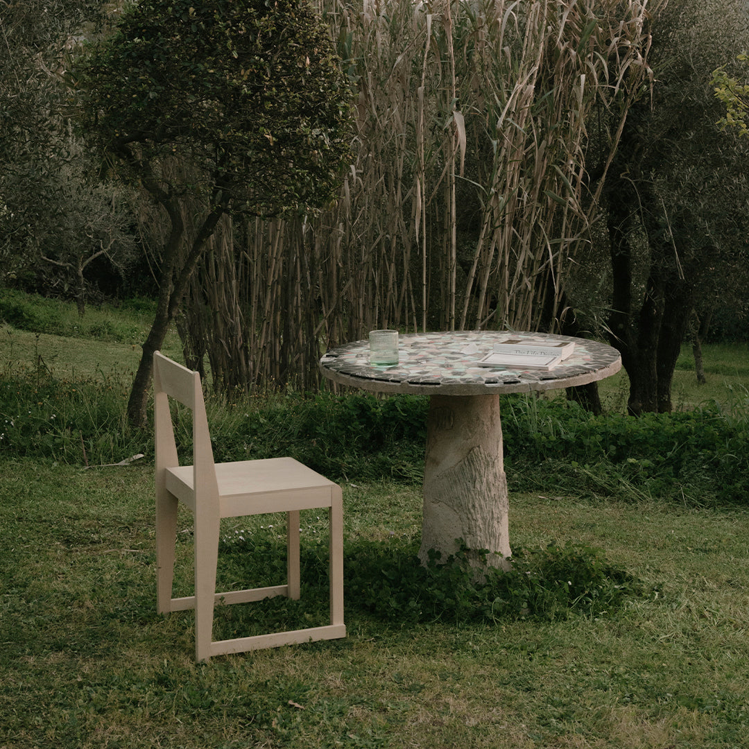"Natural stone table with a circular patterned top in earthy tones, paired with a minimalist light wood chair."