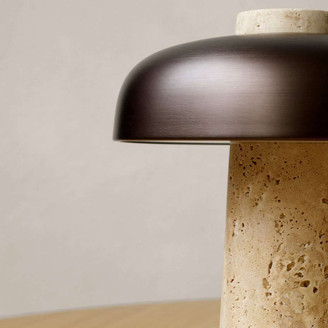 "Bronze lamp shade atop a textured beige base, creating a modern minimalist aesthetic."