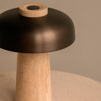 Black metal lampshade atop a smooth, beige stone base with a minimalist design and subtle textures.
