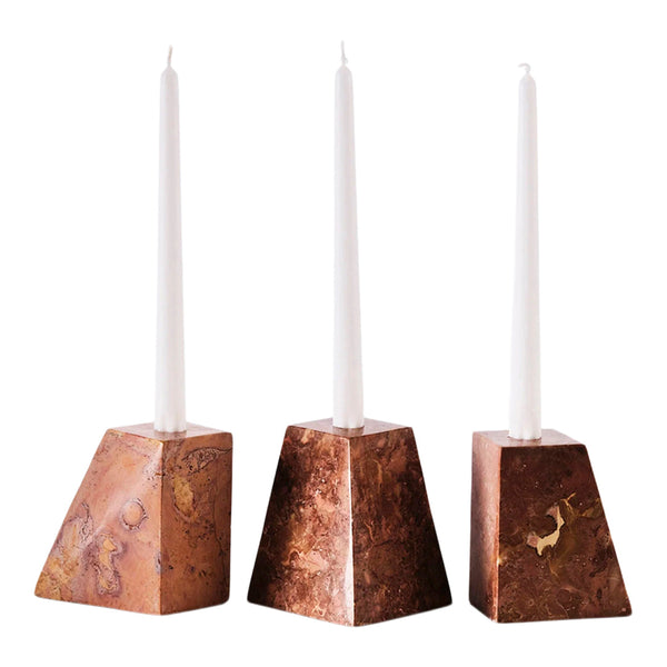 Set of three geometric candlestick holders in warm brown tones with subtle marbling, topped with white candles.