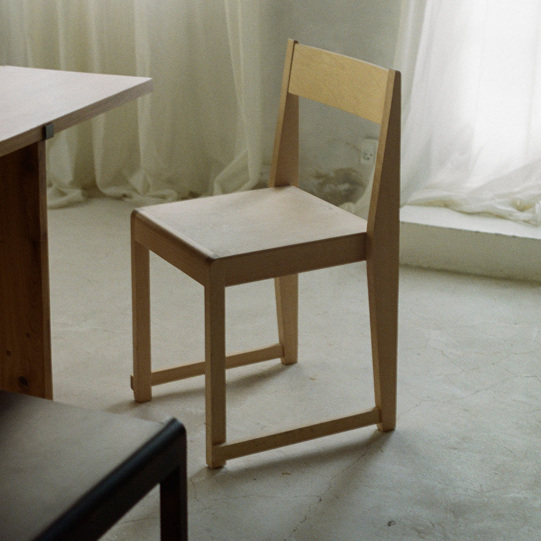 Light wooden chair with a minimalist design, featuring smooth surfaces and natural wood grain patterns.