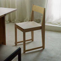 Light wooden chair with a minimalist design, featuring smooth surfaces and natural wood grain patterns.