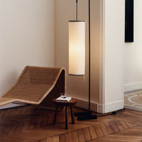 "Minimalist floor lamp with a cylindrical white shade and black metal base, complemented by natural wood textures."