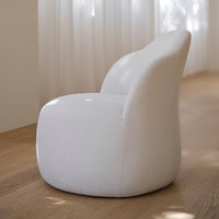 Round, soft chair in light grey fabric with subtle textured pattern, set against a warm wooden floor.