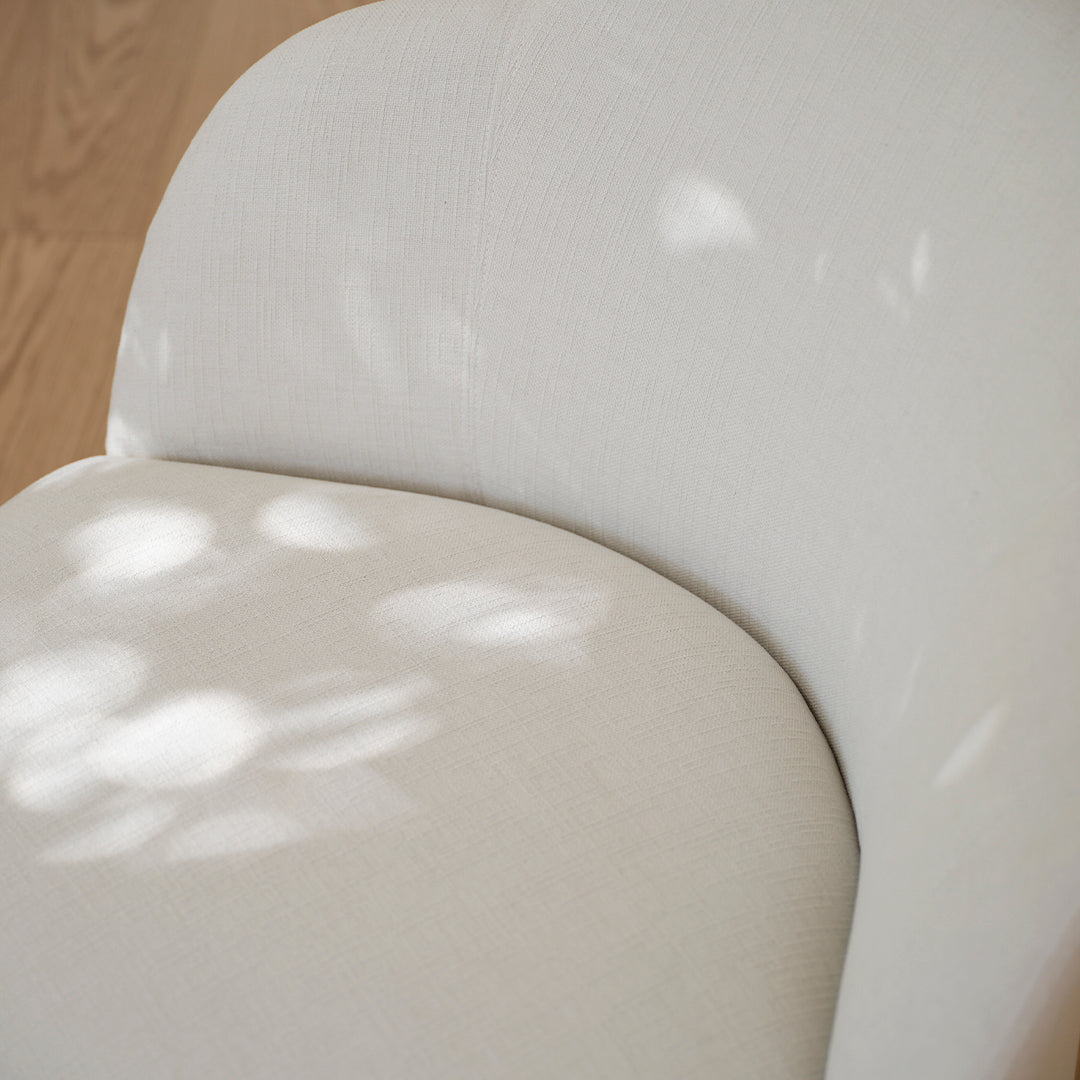 Soft beige fabric chair featuring a subtle textured pattern with light reflections. Perfect for modern decor.
