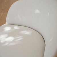 Soft beige fabric chair featuring a subtle textured pattern with light reflections. Perfect for modern decor.