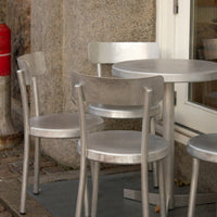 Silver metal chairs and table, featuring a sleek, modern design with a polished finish, perfect for outdoor dining.