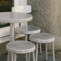 Silver metal table and stools with sleek, minimalist design, featuring smooth surfaces and geometric shapes.